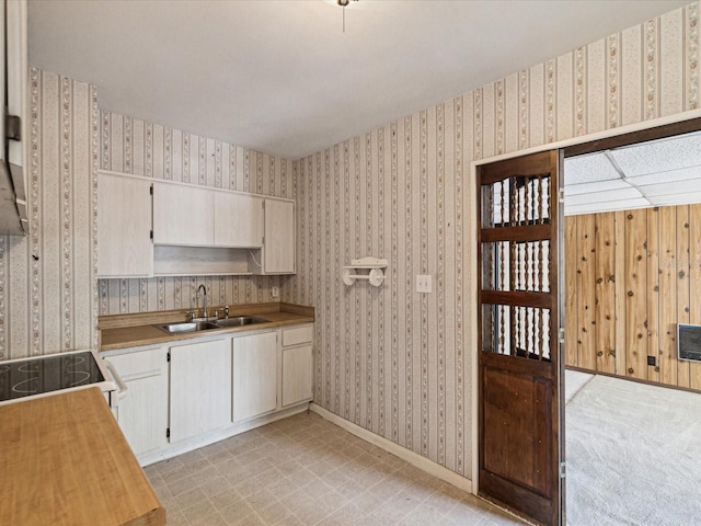 kitchen with a sink, light countertops, baseboards, electric stove, and wallpapered walls