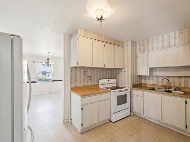 kitchen with a notable chandelier, a sink, white appliances, wallpapered walls, and light floors