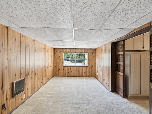 interior space with heating unit, wooden walls, and light carpet