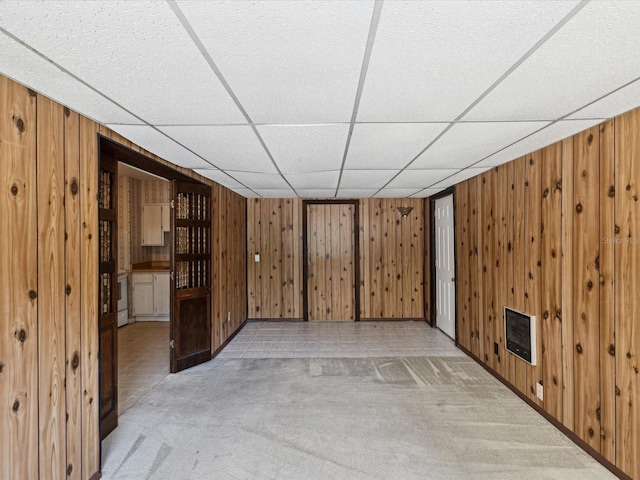 interior space featuring wooden walls, light carpet, and a paneled ceiling