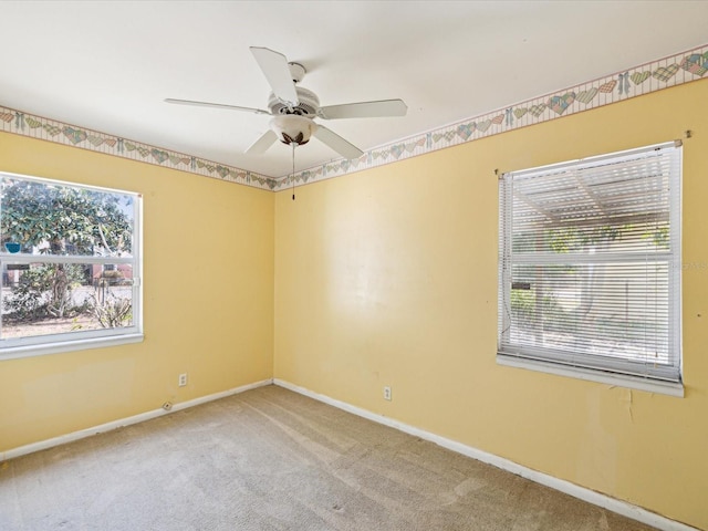spare room featuring baseboards, a ceiling fan, carpet flooring, and a wealth of natural light