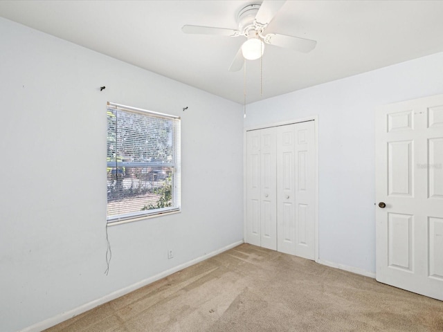 unfurnished bedroom with baseboards, light carpet, ceiling fan, and a closet