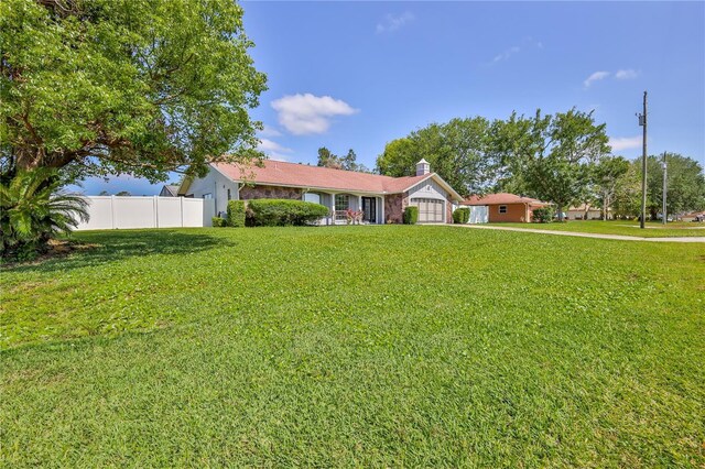 single story home featuring fence, a chimney, a front lawn, and a garage
