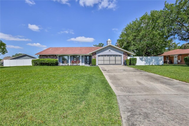 ranch-style home featuring concrete driveway, an attached garage, fence, and a front lawn