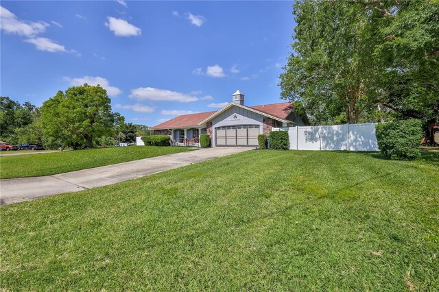 ranch-style house with an attached garage, fence, a front yard, and concrete driveway