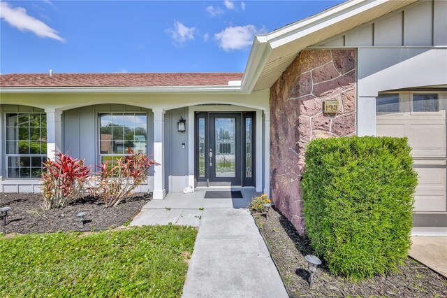 property entrance featuring a shingled roof and board and batten siding