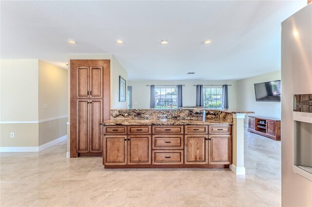 kitchen featuring brown cabinetry, marble finish floor, a peninsula, and light stone countertops