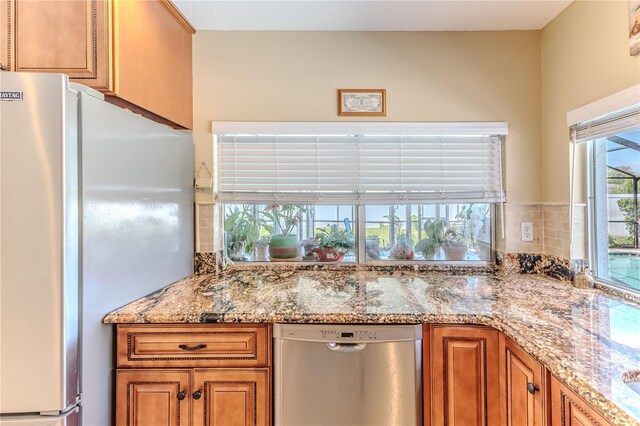 kitchen featuring tasteful backsplash, brown cabinets, light stone countertops, and stainless steel appliances