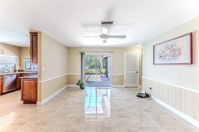 interior space with wainscoting, a ceiling fan, and visible vents