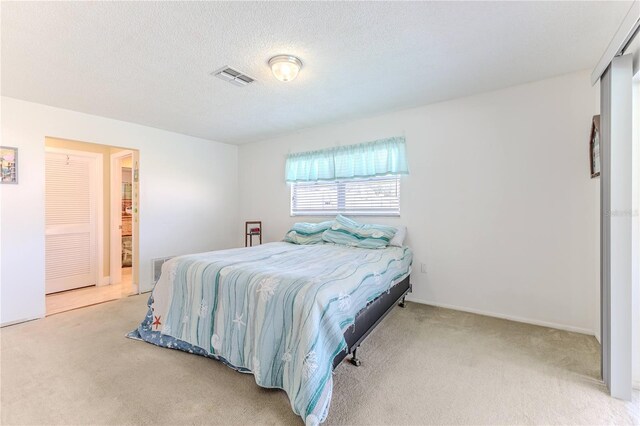 bedroom with a textured ceiling, visible vents, and carpet