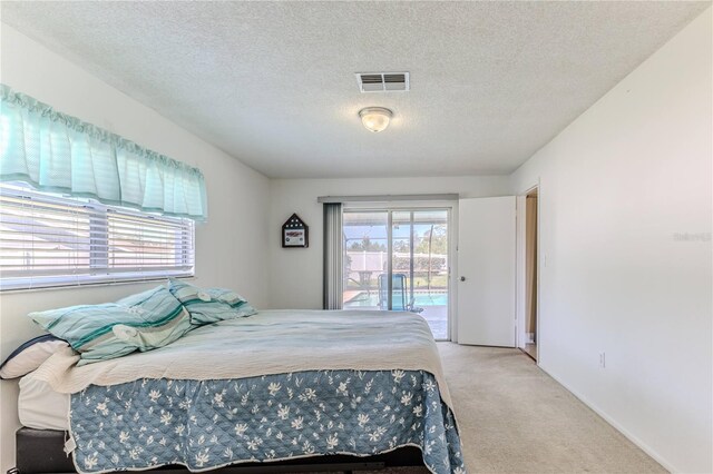 bedroom featuring a textured ceiling, access to exterior, visible vents, carpet floors, and baseboards
