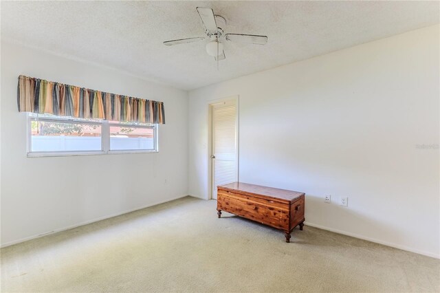 bedroom with a textured ceiling, baseboards, light colored carpet, and ceiling fan