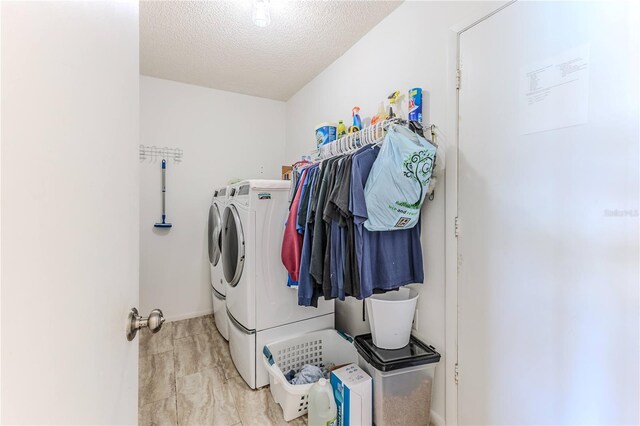 clothes washing area featuring laundry area, a textured ceiling, and washing machine and clothes dryer