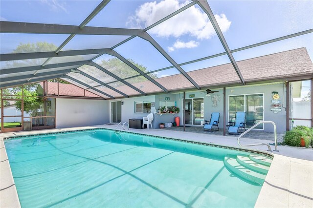 outdoor pool with glass enclosure, ceiling fan, and a patio area