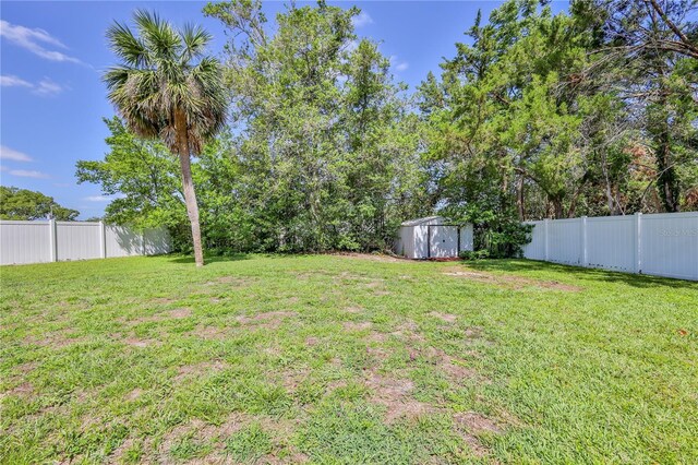 view of yard with a fenced backyard, a shed, and an outbuilding