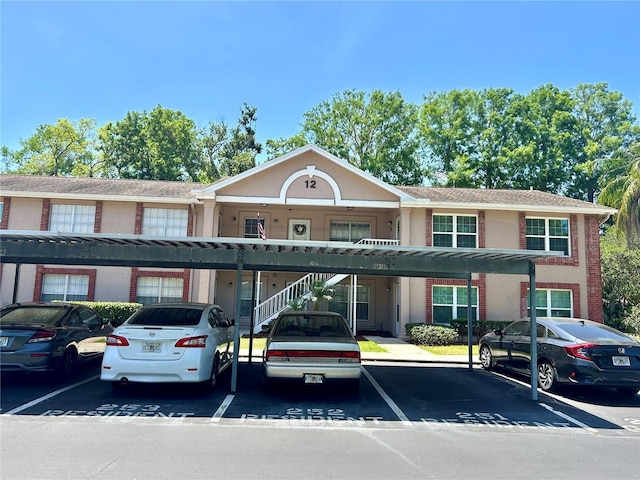 view of front of home with covered parking, stucco siding, and brick siding