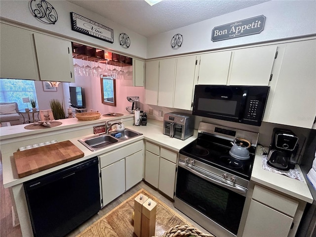kitchen featuring a sink, light countertops, a textured ceiling, white cabinetry, and black appliances