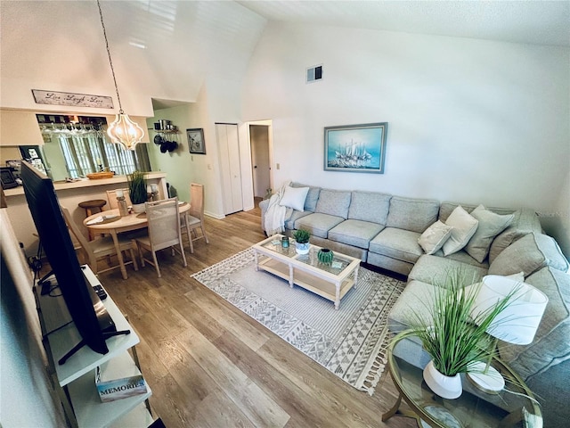 living room with high vaulted ceiling, visible vents, and wood finished floors