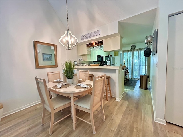 dining space with baseboards, a notable chandelier, lofted ceiling, and light wood-type flooring