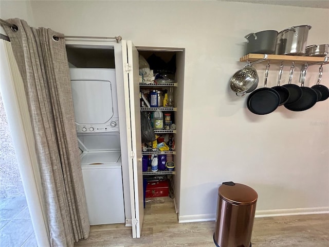 laundry area featuring stacked washer and clothes dryer, wood finished floors, and laundry area