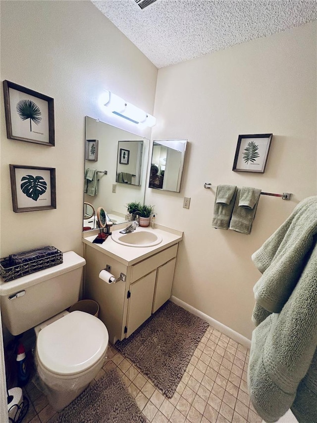 half bathroom with vanity, baseboards, toilet, and a textured ceiling