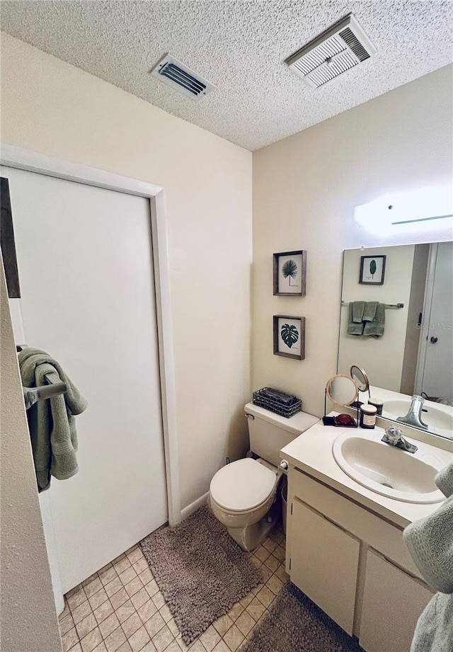 half bath with vanity, tile patterned floors, toilet, and visible vents