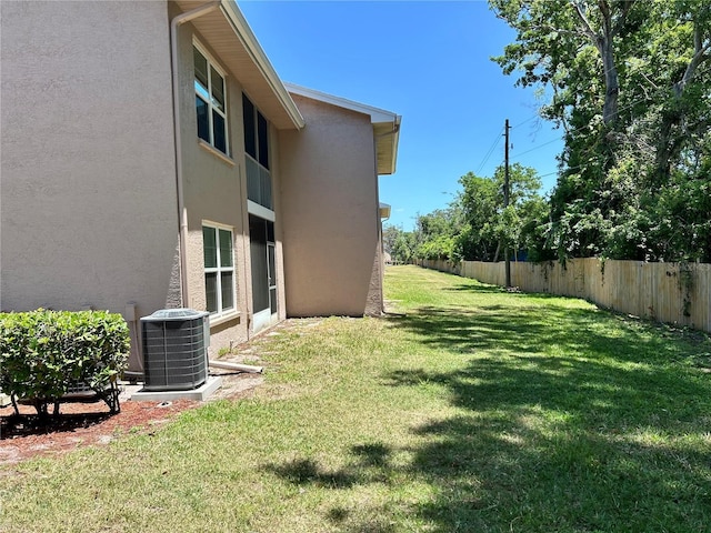 view of yard featuring central air condition unit and fence
