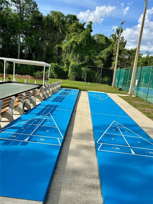 view of property's community featuring shuffleboard, a lawn, and fence