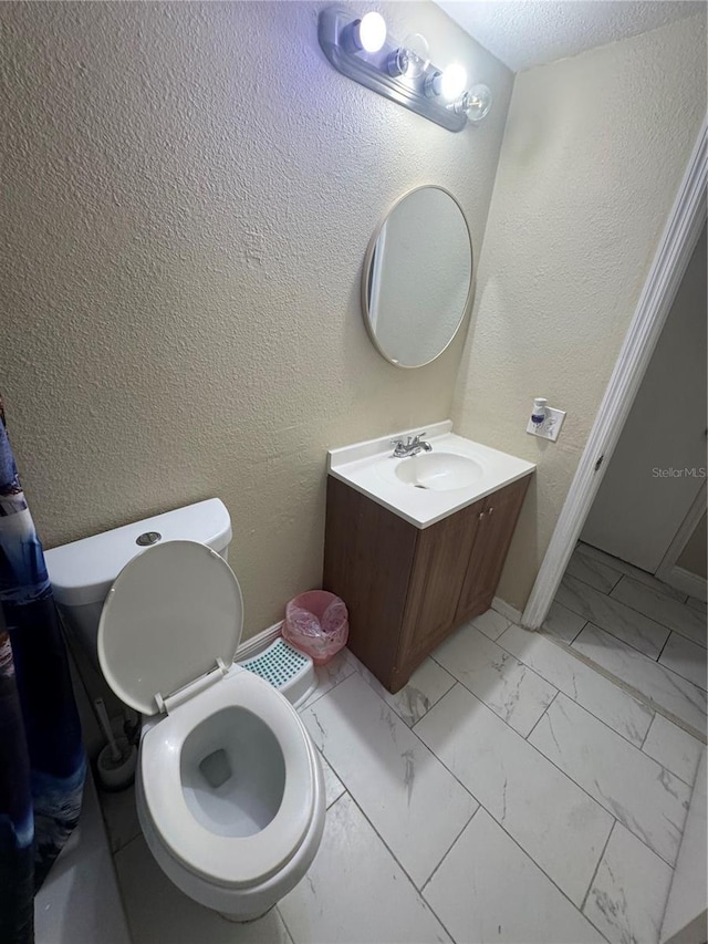 5316 Drift Tide Dr, New Port Richey, FL 34652 - bathroom with toilet, baseboards, a textured wall, marble finish floor, and vanity