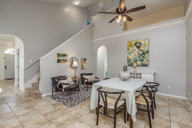 dining area with arched walkways, a high ceiling, a ceiling fan, and stairway