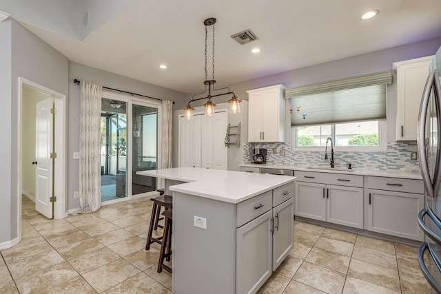 kitchen with visible vents, a sink, light countertops, and tasteful backsplash