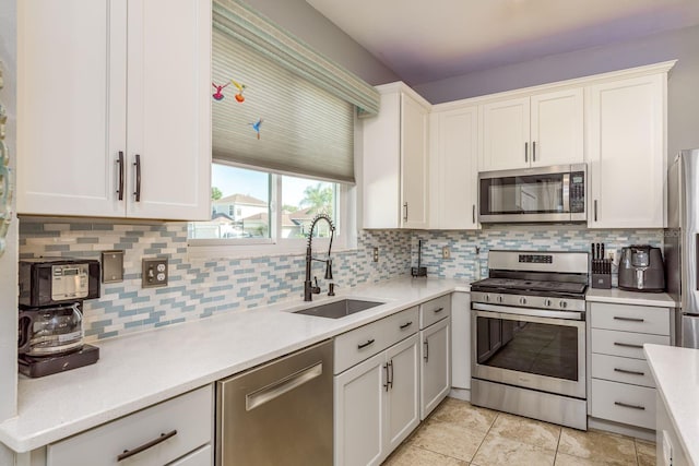 kitchen with decorative backsplash, a sink, light countertops, stainless steel appliances, and white cabinetry