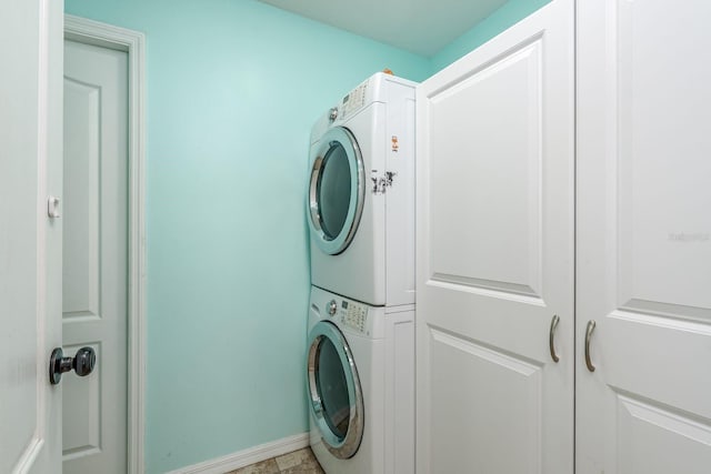 laundry room featuring laundry area, baseboards, and stacked washer / dryer