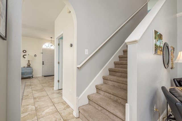 stairway featuring arched walkways, tile patterned floors, and baseboards