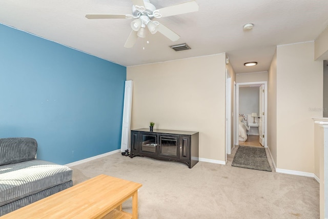carpeted living area featuring baseboards, ceiling fan, and visible vents
