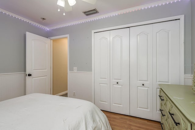 bedroom featuring visible vents, wainscoting, light wood-style floors, and a closet