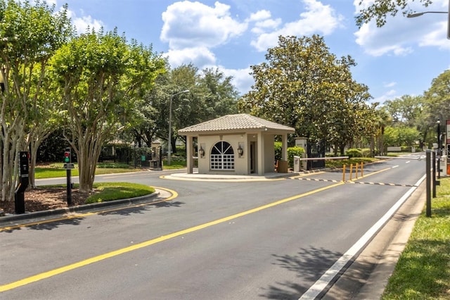 view of street featuring a gated entry, street lighting, and curbs