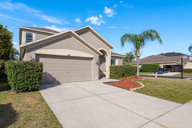 1810 Winsloe Dr, Trinity, FL 34655 - view of front of house featuring a garage, driveway, stucco siding, and a front yard