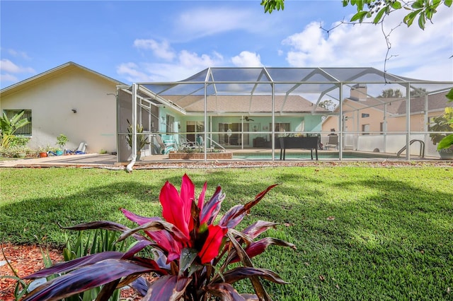 rear view of property featuring ceiling fan, a patio, an outdoor pool, stucco siding, and a yard