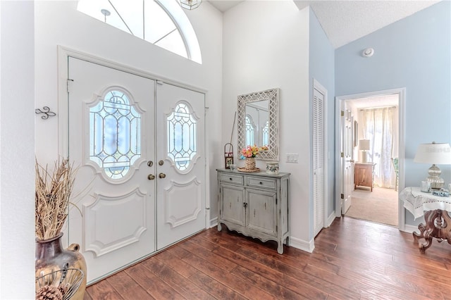 entryway featuring french doors, baseboards, dark wood-type flooring, and a high ceiling