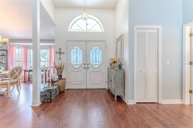 entrance foyer featuring plenty of natural light, a towering ceiling, wood finished floors, and a notable chandelier