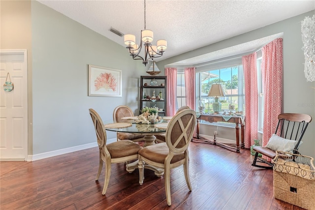 dining room with a textured ceiling, wood finished floors, baseboards, lofted ceiling, and an inviting chandelier