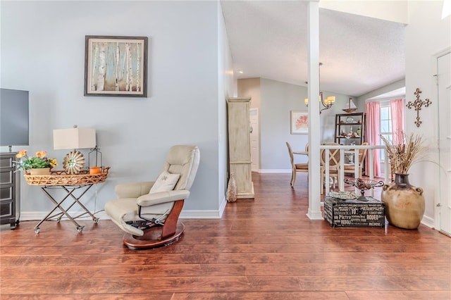 living area with a notable chandelier, baseboards, vaulted ceiling, and wood finished floors