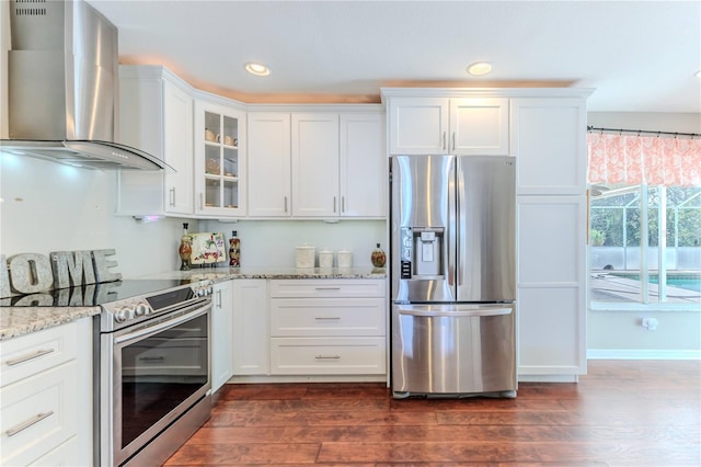 kitchen featuring appliances with stainless steel finishes, white cabinets, glass insert cabinets, wall chimney exhaust hood, and dark wood-type flooring