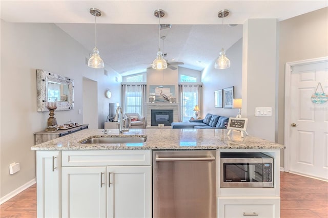 kitchen with a ceiling fan, appliances with stainless steel finishes, a sink, and light wood finished floors