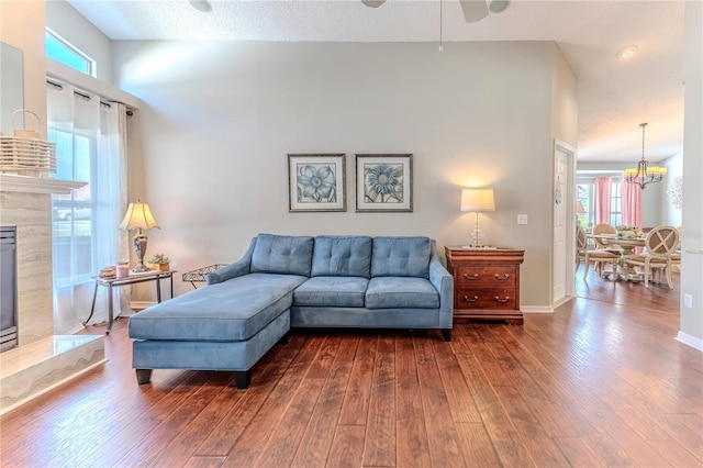 living room with dark wood-style flooring, a healthy amount of sunlight, ceiling fan with notable chandelier, and a fireplace