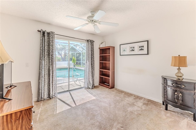 interior space featuring baseboards, ceiling fan, carpet, and a textured ceiling