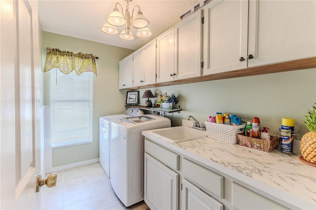 washroom featuring washing machine and clothes dryer, light tile patterned flooring, cabinet space, a sink, and a chandelier