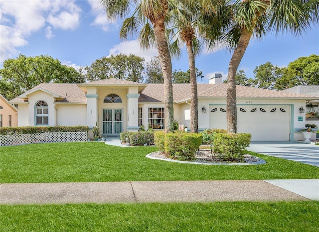 view of front facade featuring an attached garage, stucco siding, driveway, and a front yard