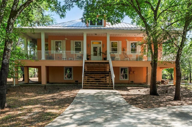view of property with covered porch, french doors, a standing seam roof, stairs, and metal roof
